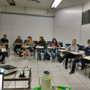 Sala de aula com muitas cadeiras e pessoas sentadas em círculo.