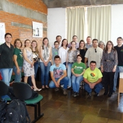 Grupo de pessoas sorridentes em pé e sentadas, dentro de uma sala de aula.