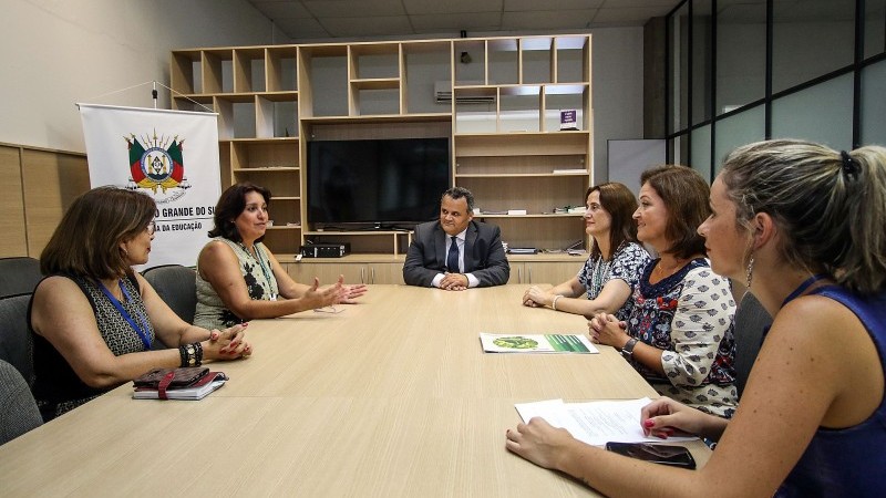 Ao redor de uma mesa, os participantes da reunião.