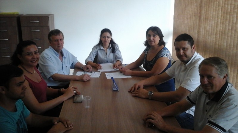 Ao redor de uma mesa, as pessoas que participaram do ato de assinatura da escritura.
