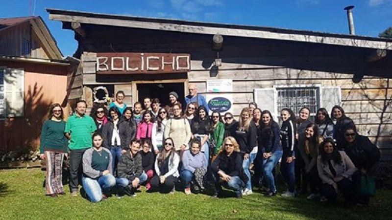 Nove pessoas agachadas e outras vinte e seis em pé posam para a foto em frente à recepção do Bolicho do Chapéu.
