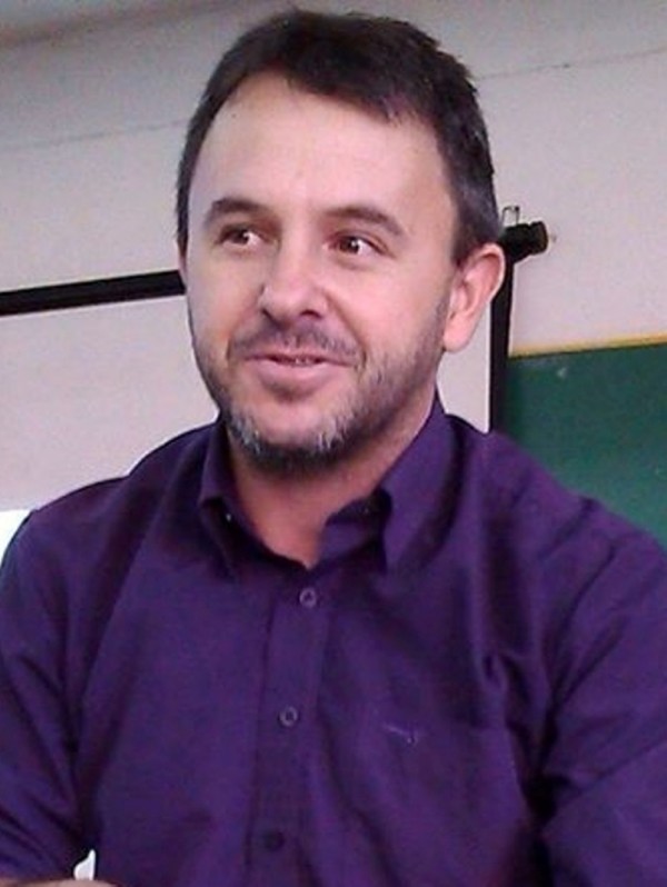 Homem de pele morena clara, olhos e cabelos escuros, curtos, barba rala.