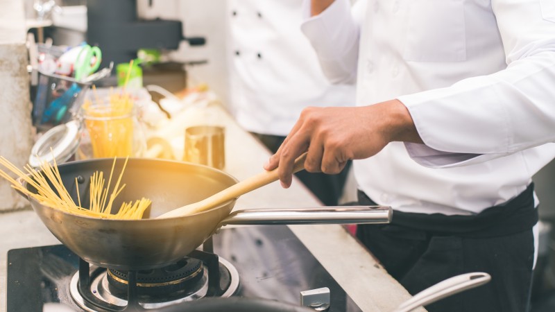 Chefe de cozinha cozinhando uma massa espaguete em uma panela com um cabo.