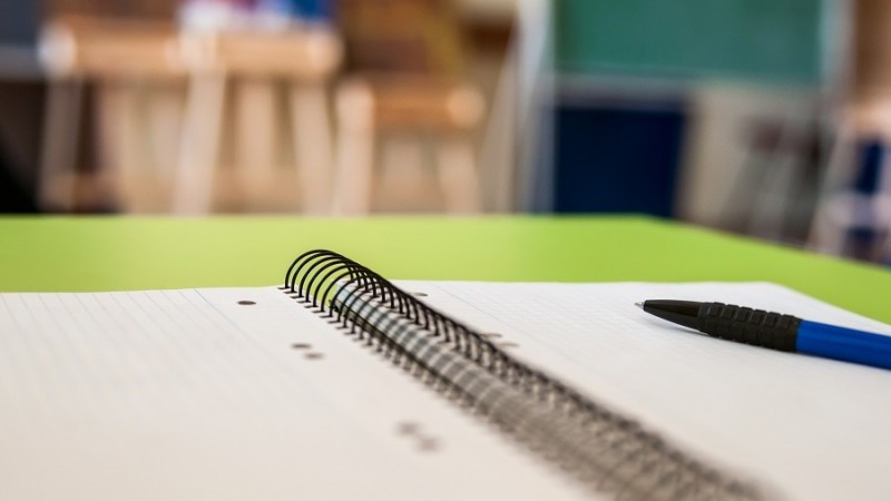 Caderno espiral aberto com um lápis sobre uma mesa.