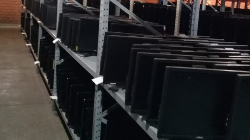 Diversos computadores organizados em estante de metal.
