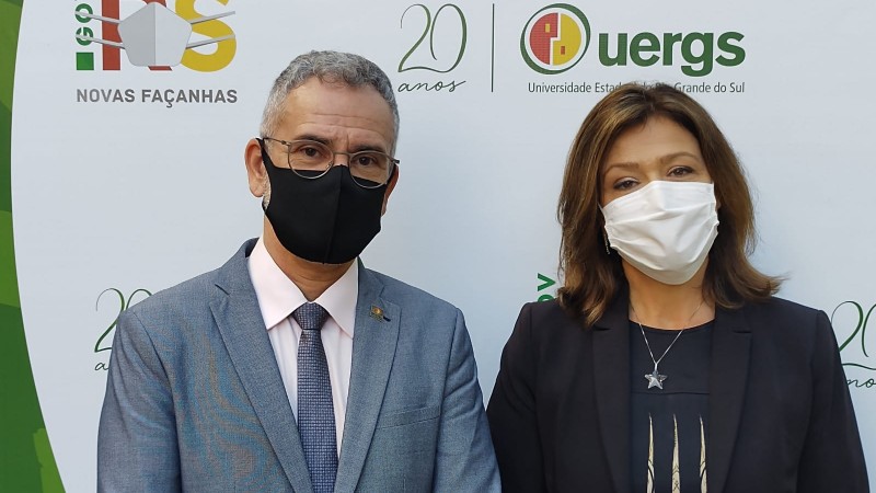Foto colorida. À esquerda, o reitor, homem de meia-idade, branco, com cabelos grisalhos, usa óculos de grau, terno e gravata em tom cinza com camisa branca, e máscara de proteção facial. À direita, a vice-reitora, mulher de meia-idade, branca, de cabelos castanhos claros na altura do ombro, usa blaser e blusa pretos, e máscara de proteção facial.