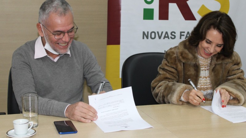 Foto colorida. À esquerda, reitor da Uergs sorridente assinando o documento. À direita, secretária da Seduc assinando o documento.
